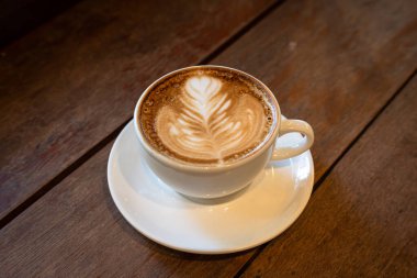 Sütlü sütlü sütlü sütlü sıcak kahve fincanı ahşap masanın üstünde. Kafedeki bir kafede kahvaltı olarak, iş konsepti sırasında, klasik tarzda.