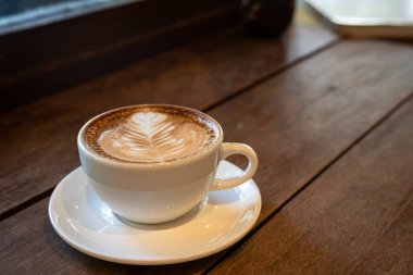 Sütlü sütlü sütlü sütlü sıcak kahve fincanı ahşap masanın üstünde. Kafedeki bir kafede kahvaltı olarak, iş konsepti sırasında, klasik tarzda.