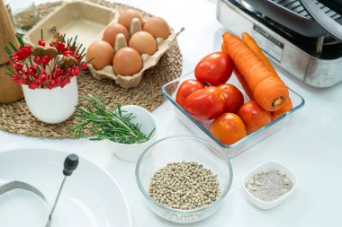 Cam bardakta biber, sebze, domates, yumurta ve beyaz masadaki mutfakta çırpı. Düz yatıyordu. Yemek hazırlama kavramı, arka planda mutfak..