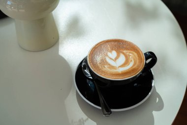 Sütlü sütlü sütlü sütlü sıcak kahve fincanı ahşap masanın üstünde. Kafedeki bir kafede kahvaltı olarak, iş konsepti sırasında, klasik tarzda.