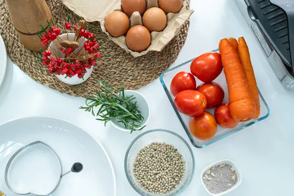 Cam bardakta biber, sebze, domates, yumurta ve beyaz masadaki mutfakta çırpı. Düz yatıyordu. Yemek hazırlama kavramı, arka planda mutfak..