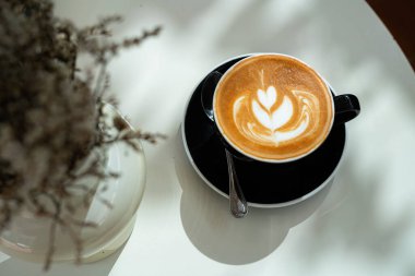 Sütlü sütlü sütlü sütlü sıcak kahve fincanı ahşap masanın üstünde. Kafedeki bir kafede kahvaltı olarak, iş konsepti sırasında, klasik tarzda.