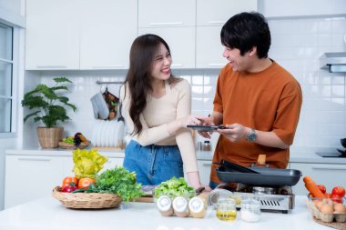 Mutlu Aile portresi, neşeli bir yemek hazırlayan Asyalı 'yı sevmenin mutlu portresi. Tablette et, ekmek pişirirken bir yandan da evde ya da mutfakta yemek pişirmenin keyfini çıkar.