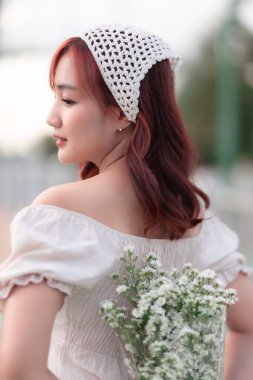 Asyalı güzel bir kadının portresi. Manken, yaz elbisesi giymiş genç bir kız. Köprüde duruyor..