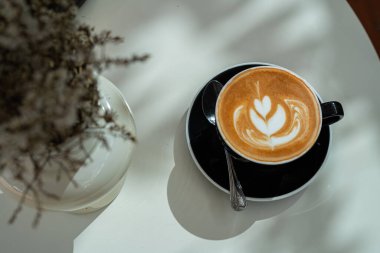 Sütlü sütlü sütlü sütlü sıcak kahve fincanı ahşap masanın üstünde. Kafedeki bir kafede kahvaltı olarak, iş konsepti sırasında, klasik tarzda.