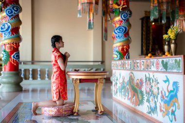 Portre güzel sevimli gülümseme kırmızı keongsam elbise giyen Asyalı genç kadın Çin Yeni Yıl Festivali için geleneksel dekorasyon Çin kültürünü Tayland 'daki Çin tapınağında kutluyor.