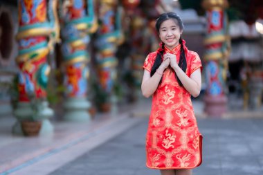 Portre güzel sevimli gülümseme kırmızı keongsam elbise giyen Asyalı genç kadın Çin Yeni Yıl Festivali için geleneksel dekorasyon Çin kültürünü Tayland 'daki Çin tapınağında kutluyor.