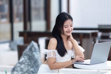 Asyalı serbest gençlerin, iş kadınlarının, kafenin arka planında dizüstü bilgisayarla çalışan iş kadınlarının portresi, güveni artıran ve başarılı bir konsept oluşturdu.