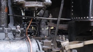 Buharlı tren motorunun detaylı görüntüsü. Siyah tren kompozisyonu, istasyonda bekliyor. 4K