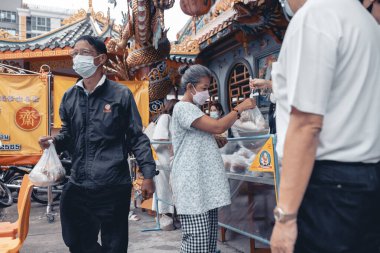 Chiangmai, Tayland - 30 Eylül 2022: Fakir ve aç olanlar gönüllülerden yıllık vejetaryen festivali için bedava yemek almak için sıraya girdiler: gıda bağışı kavramı