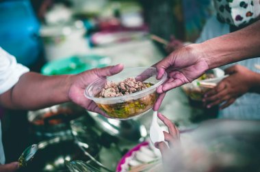 Gönüllülerden bedava yemek isteyen aç dilencilerin elleri. Verme ve paylaşma kavramı.