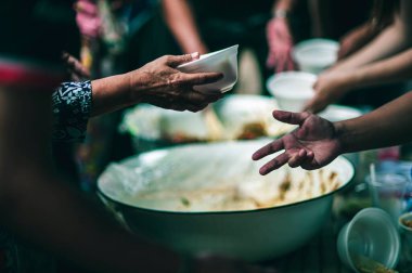 Gönüllülerden bedava yemek isteyen aç dilencilerin elleri. Verme ve paylaşma kavramı.