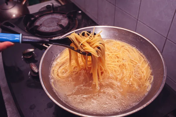 Pasta is cooked in boiling water in a pan.