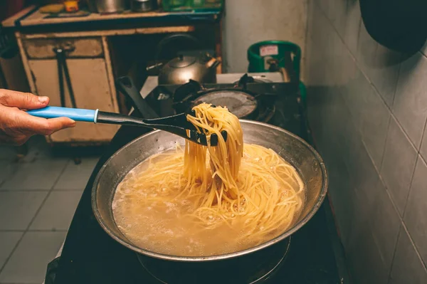 Pasta is cooked in boiling water in a pan.