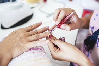 Manikürcü, ellerin güzelliği için tırnakları süslüyor..