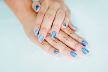 İnci mavisi boyayla oje süren Asyalı bir kadının elleri..