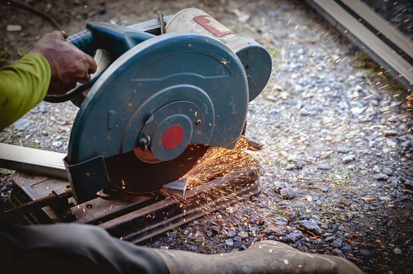 The industrial use of a metal cutting saw involves heat and sparks from skilled technicians.