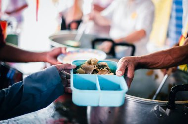 The hands of the poor apply for food from rich people who donate food.