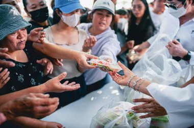 Chiang Mai - Tayland 25 Kasım 2023: Köylüler geleneksel yerel festivalde yiyecek dağıtan gönüllülerden bedava yemek almaya geliyorlar. Tayland 'ın Chiang Mai şehrinde.