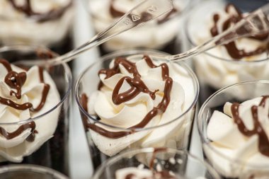 Çukulata ve krem şantili tatlı. Tatlı masasında küçük plastik fincanlar, çikolatalı kurabiye sosları ve tatlı masasında çikolatalı kurabiye sosları.