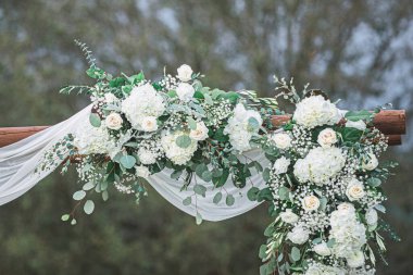Beyaz ortanca buketleri beyaz perdelerle akan düğün kemeri dekoru gibidir.