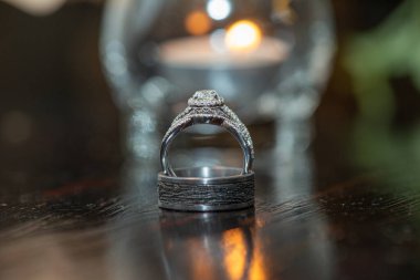 Gümüş nişan yüzükleri. Yansıtıcı ahşap yüzey ve bokeh arka plan.