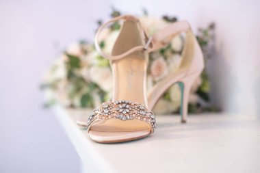 Gelinlik çiçeği buketinin önünde suni elmaslarla süslenmiş zarif gelinlik ayakkabıları.