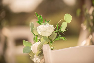 Beyaz koltuklarda beyaz güller, açık havada düğün töreni.