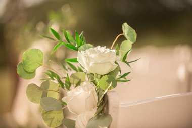 Beyaz koltuklarda beyaz güller, açık havada düğün töreni.