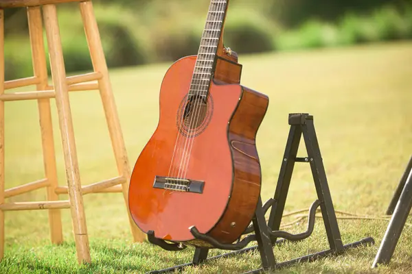 stock image Wood violin guitar on guitat stan on green grass at beautiful wedding