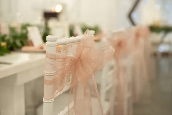 stock image Amazing bottle of red wine with black cap and blank white label on wood table with warm romantic background chivari chairs decorated and drapped with beige lace bows at wedding reception dinner setting with white tables.