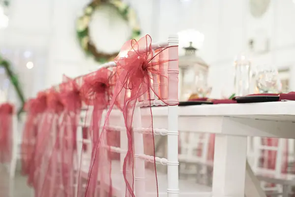 stock image Stunning rows of chivari chairs decorated and drapped with red lace bows at wedding reception dinner setting with  long white tables elegantly set