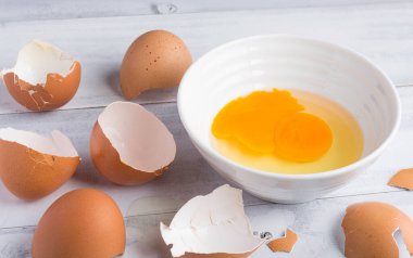 Çiğ tavuk yumurtası, yumurta sarısı beyaz ahşap kasede.