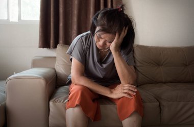 Yaşlı Asyalı kadın evde baş ağrısı ve akıl sağlığı sıkıntısı çekiyor.