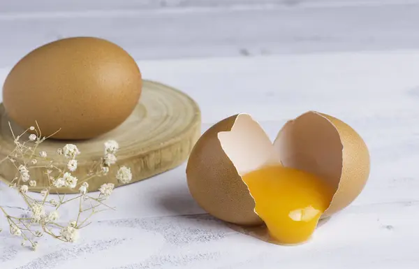生破碎的鸡蛋 蛋黄在白色木壳上 图库图片