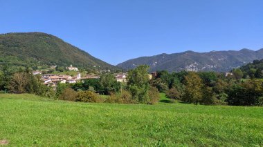 Arka planda küçük bir köy olan güzel bir dağ manzarasının dikey görüntüsü.