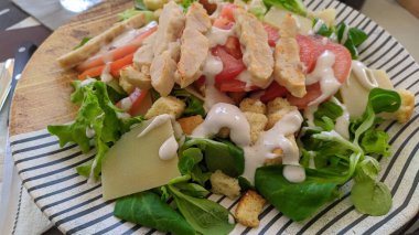 Tavuk, domates, marul ve soslu bir salata.