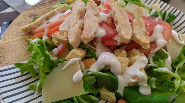 Tavuk, domates, marul, peynir ve soslu bir salata.