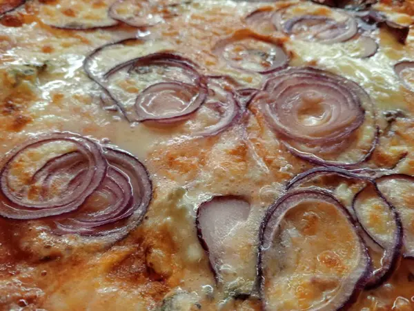 a pizza with onions on it sitting on a table
