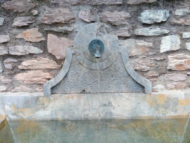 Büyük bir çeşmesi olan eski taş bir duvar.