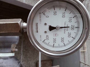 Eski tuğla duvarın arka planında basınç göstergesi.