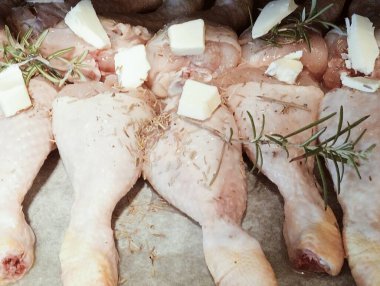 Çiğ tavuk budu biberiye, yağ ve tereyağlı fırında pişirmeye hazır.