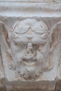 Eski bir binanın duvarında genç bir adamın heykeli.