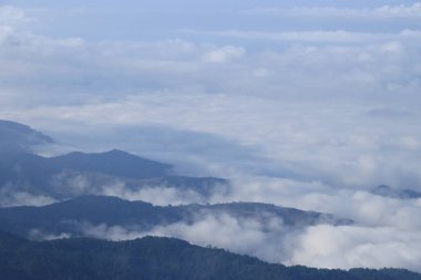 Gökyüzünde süzülen beyaz bulutlu karmaşık dağlar