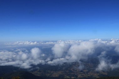 Beyaz bulutlar dağların üzerinde kümeler halinde yüzerler..