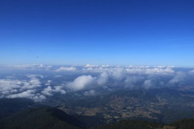 Beyaz bulutlar dağların üzerinde kümeler halinde yüzerler..