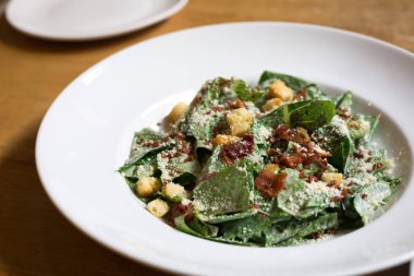 Caesar Salad on white plate on the wood table in restaurant.