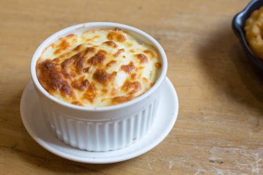 Cheese mashed potatoes in white cup on the wood table in restaurant.