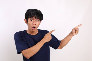 Yan tarafı göstererek ayakta duran Asyalı genç adam şaşırdı. Kopyalama alanı ile beyaz arkaplanda izole