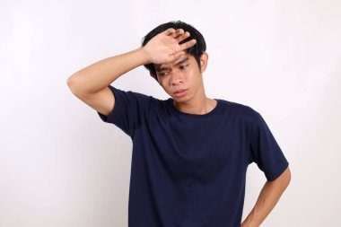 Asyalı genç adam yorgun bir jestle ve ateşli hissederek ayakta duruyor. Beyaz arkaplanda izole